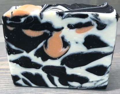 a photo of animal instinct soap with striking white and black sections with orange accents