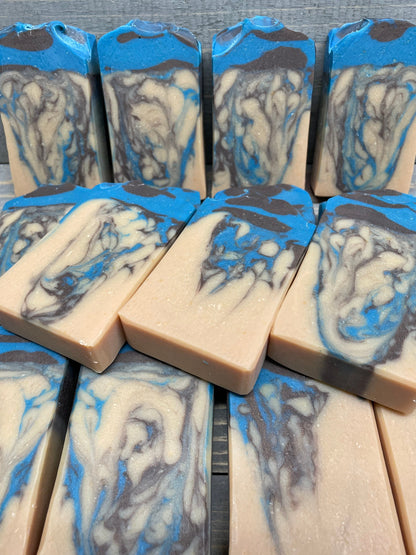 A photo of Beachwood Vetiver Goat Milk Soap with light blue and gray accent of a creamy color bar