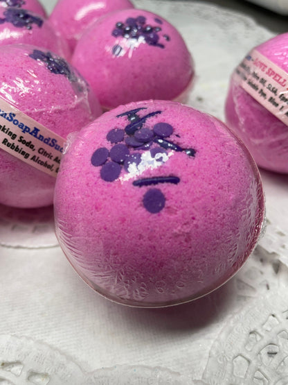 a photo of several Love Spell flower and fruit scented Bath Bombs, Love Spell with Embeds in pink with purple accents