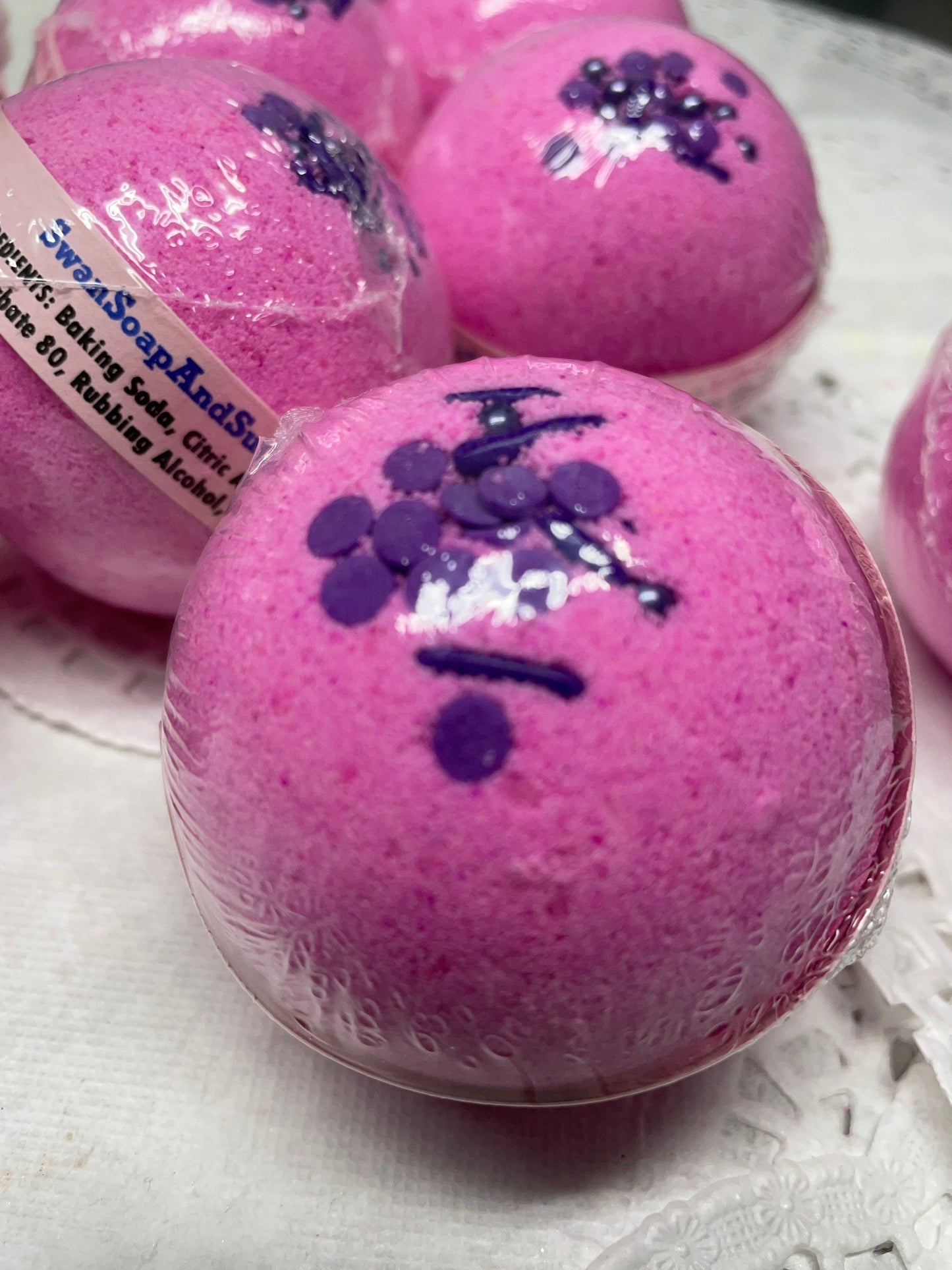 a photo of several Love Spell flower and fruit scented Bath Bombs, Love Spell with Embeds in pink with purple accents