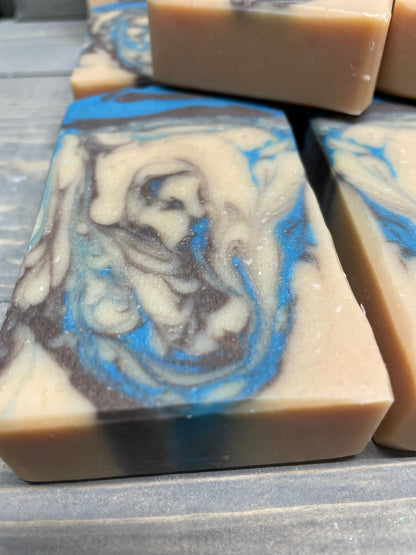 A photo of Beachwood Vetiver Goat Milk Soap with light blue and gray accent of a creamy color bar