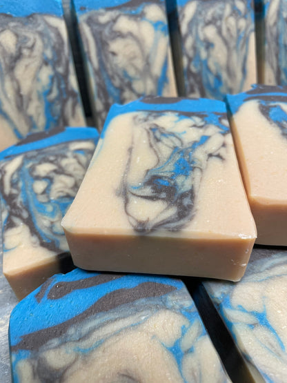 A photo of Beachwood Vetiver Goat Milk Soap with light blue and gray accent of a creamy color bar