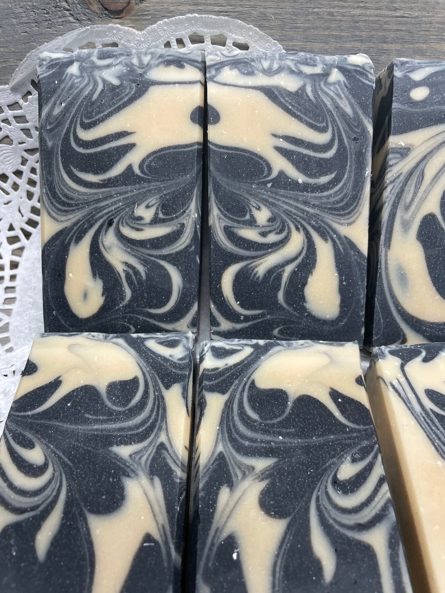 A photo of Goat Milk and Charcoal Soap bar soap with black and cream colored bars. 