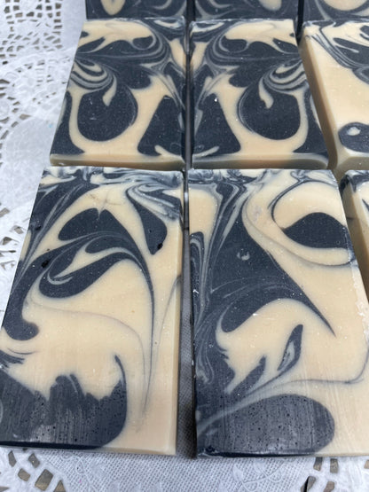 A photo of Goat Milk and Charcoal Soap bar soap swirled with black and cream colored  bars. 