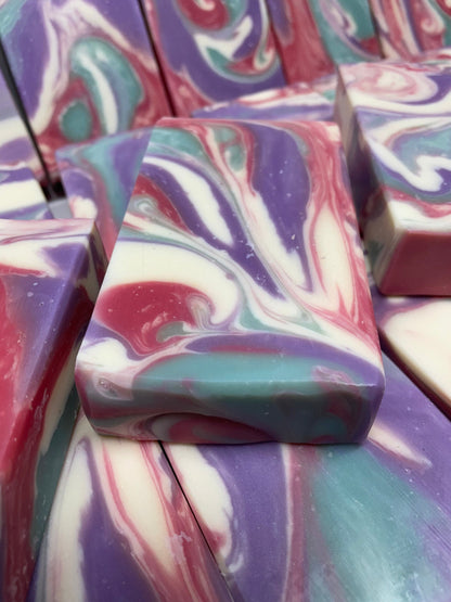 A photo of Love Spell Soap with a swirl of sea moss color, lavender color, creamy color, and red color