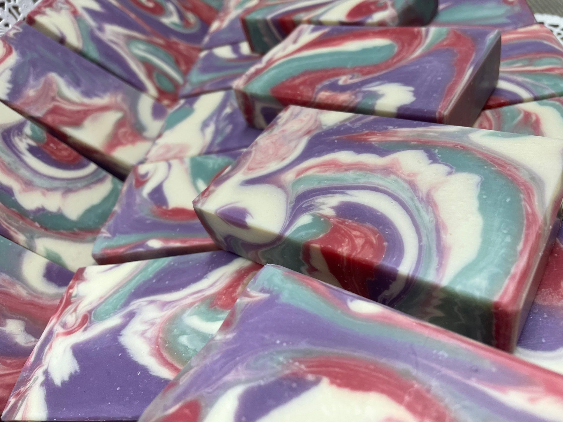 A photo of Love Spell Soap with a swirl of sea moss color, lavender color, creamy color, and red color