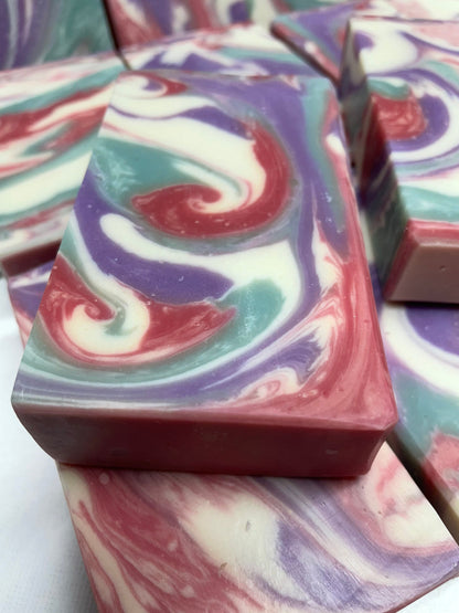 A photo of Love Spell Soap with a swirl of sea moss color, lavender color, creamy color, and red color