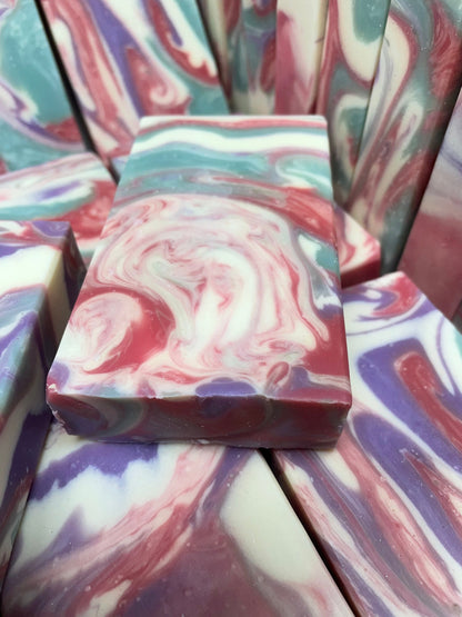 A photo of Love Spell Soap with a swirl of sea moss color, lavender color, creamy color, and red color